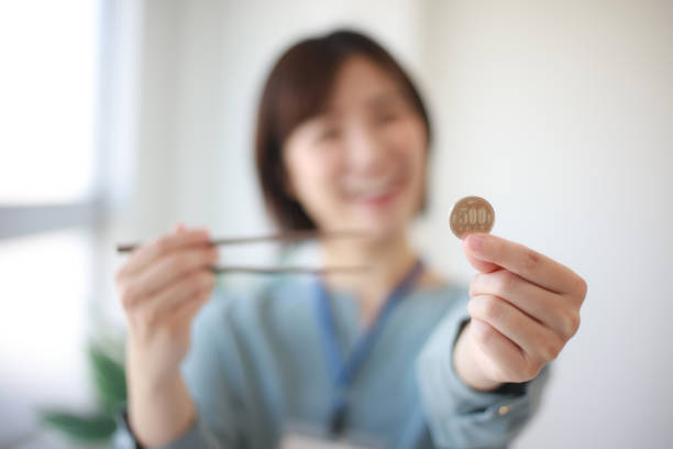 wanita memegang koin 500 yen dan sumpit sambil terrsenyum